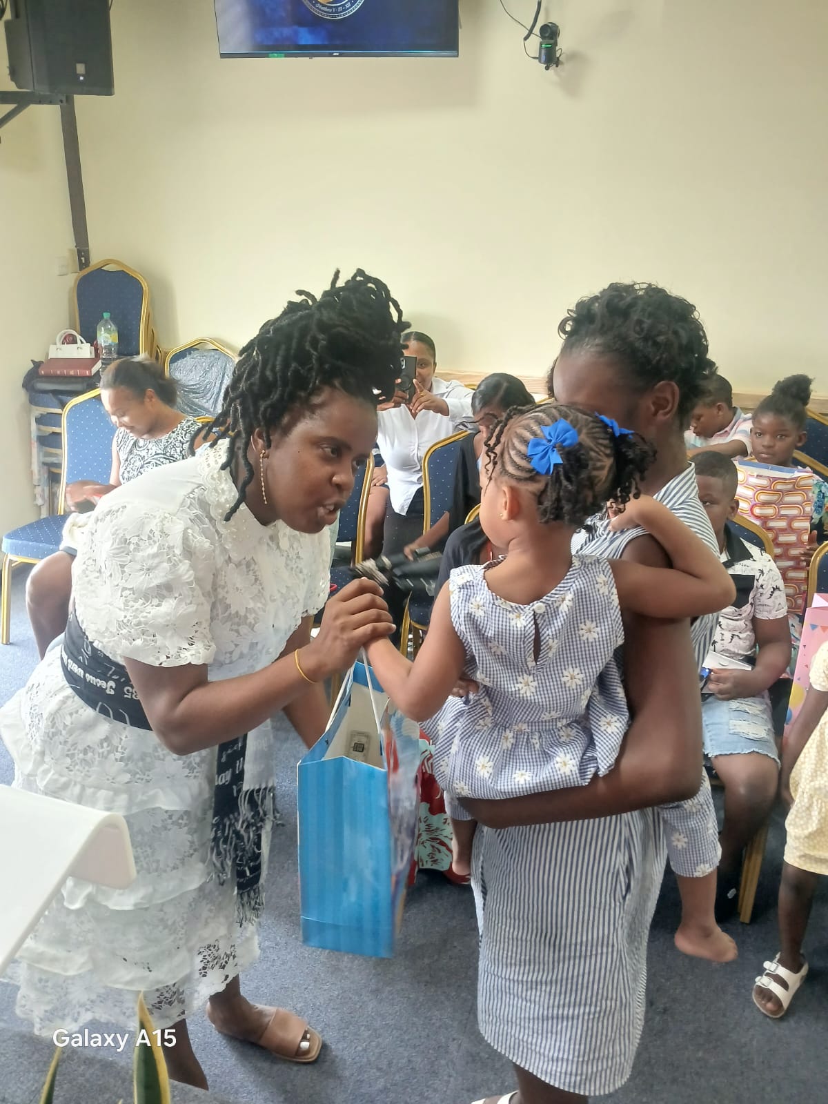 Church leader giving a gift to a girl wearing a blue bow